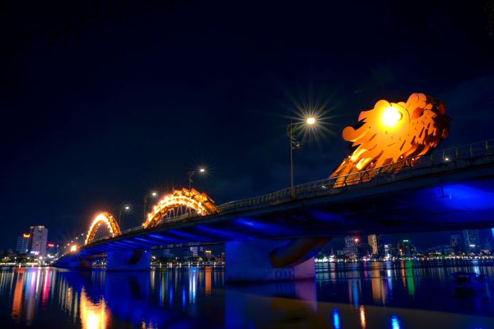 Dragon Bridge (Cầu Rồng) is an iconic landmark in Da Nang, known for its stunning design and vibrant displays. Spanning the Han River, this magnificent bridge is shaped like a dragon, symbolizing power and good fortune in Vietnamese culture. At night, the bridge comes alive with colorful LED lights, creating a captivating spectacle for visitors. On weekends and special occasions, the dragon breathes fire and water, delighting onlookers and adding to the bridge's allure. With its breathtaking views and impressive architecture, Dragon Bridge is not only a vital transportation link but also a popular destination for tourists and locals alike, embodying the spirit of Da Nang.