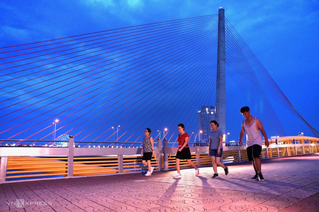 Visitors walking along Nguyen Van Troi Bridge in Da Nang, enjoying the scenic views of the river and surrounding landscape, creating a peaceful atmosphere.