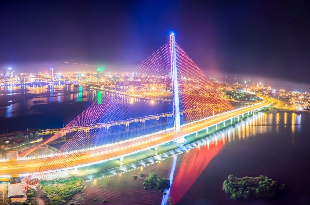 . Tran Thi Ly Bridge illuminated at night, showcasing vibrant, colorful lights against the dark sky.