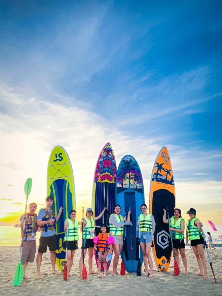 Family posing together on SUP board, with Man Thai beach as background.