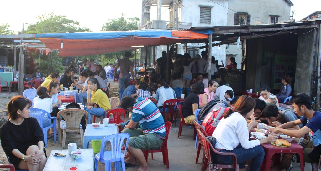 Hình ảnh 20 năm trước của bánh canh cá cô Cúc với nhà dựng tạm với mái che bạt xanh.Quán đông nghịt người.