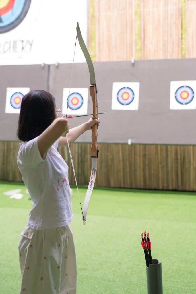 A row of people shooting arrows during an archery session, all focused on their targets.