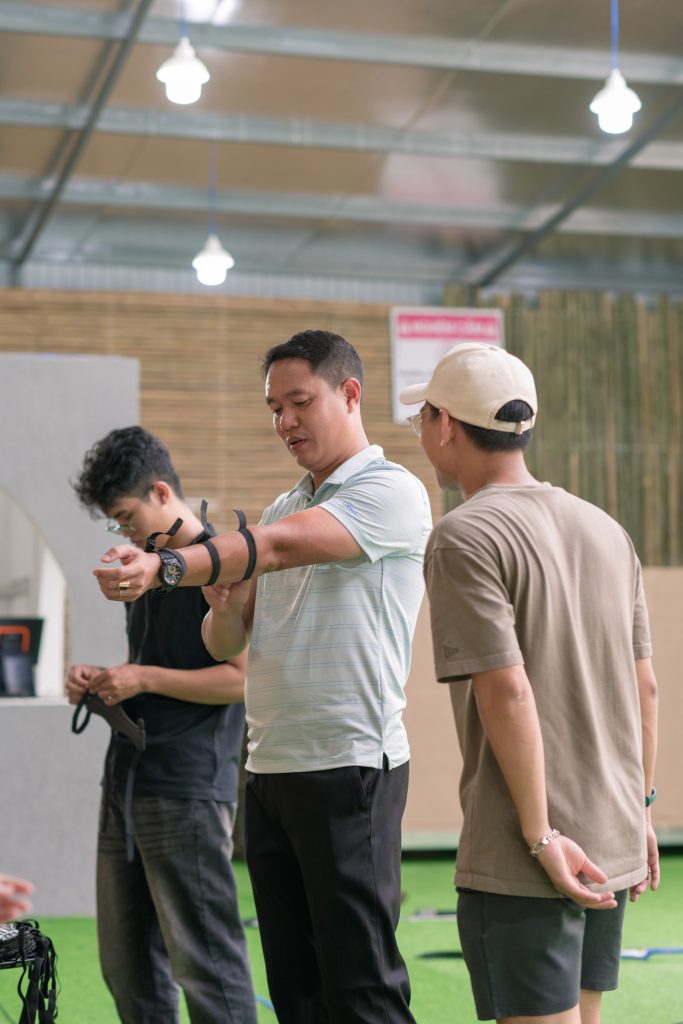 A man instructing others on how to shoot a bow, providing guidance during an archery lesson.