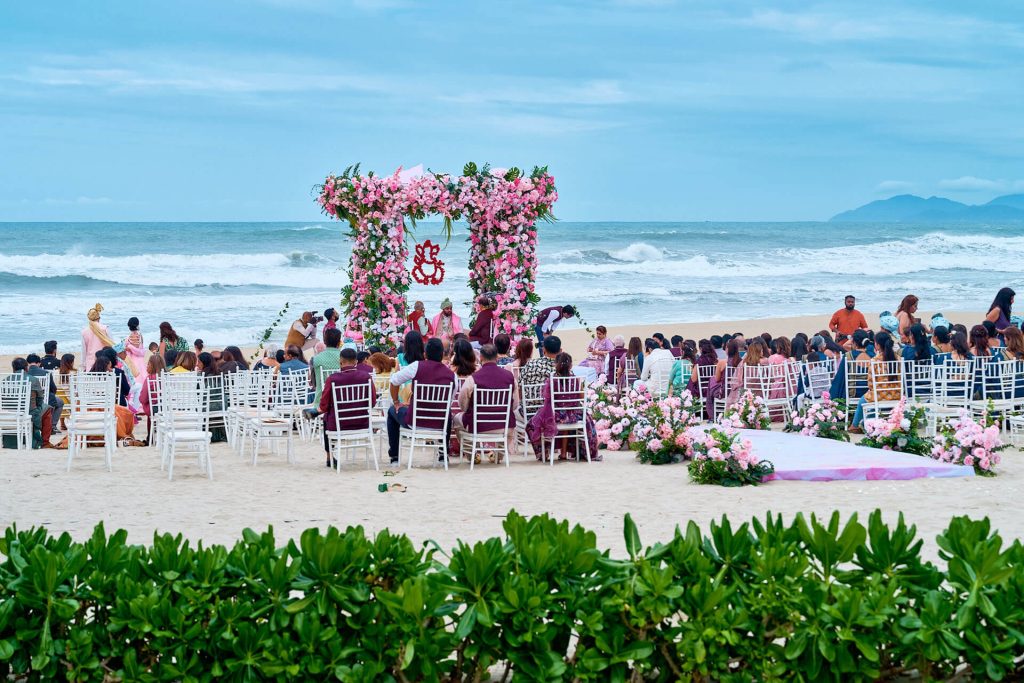 A beautiful Indian wedding takes place by the beach, featuring vibrant traditional attire, stunning decorations, and a picturesque beach backdrop.