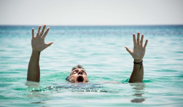 A man appears to be struggling in the water, conveying a sense of urgency and distress.