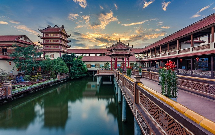 The tranquil lake at Nam Son Pagoda, reflecting the blue sky and surrounded by trees.