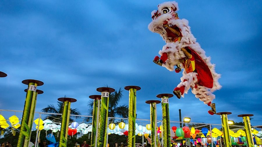 A lion performing acrobatic stunts on the river near downtown Da Nang, showcasing traditional culture in a vibrant setting