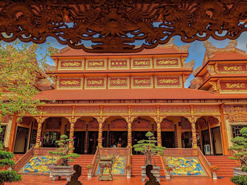 A view of Nam Son Pagoda in Da Nang, featuring ornate carvings and colorful decorations on the temple's façade, surrounded by lush greenery and a clear blue sky.