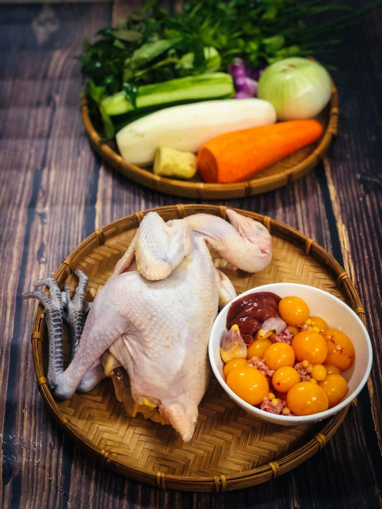 A variety of fresh ingredients for chicken rice, including chicken, rice, herbs, and pickled vegetables