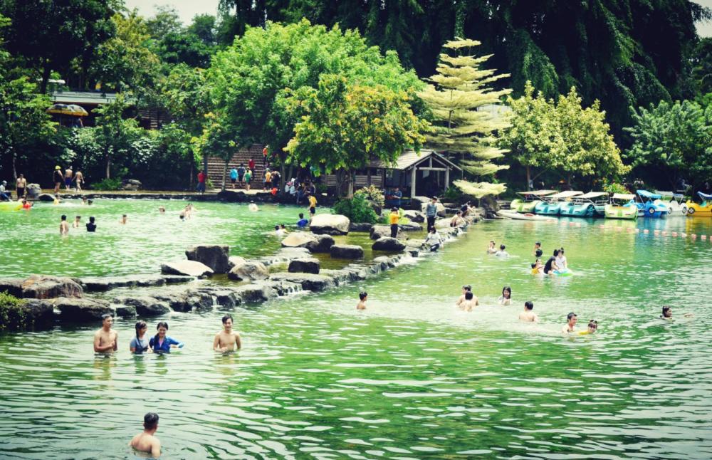 Tourists relaxing and bathing under the cool waterfall at Suoi Mo