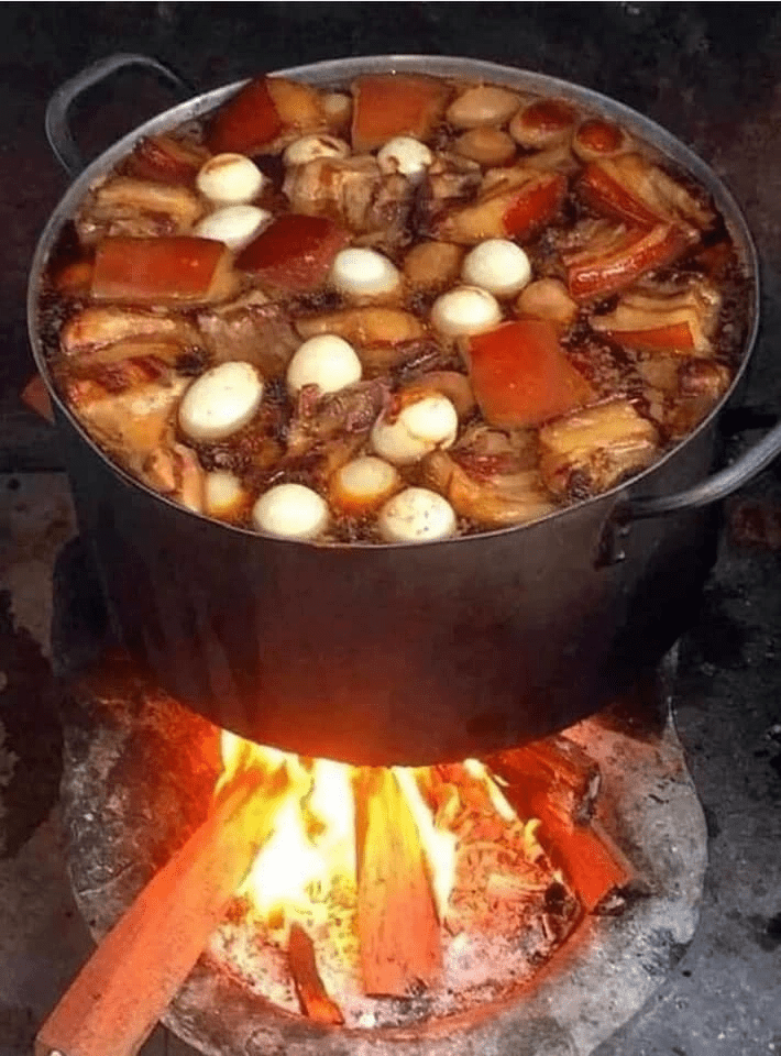 A traditional pot filled with meat cooking over an open fire, representing Tet holiday festivities.
