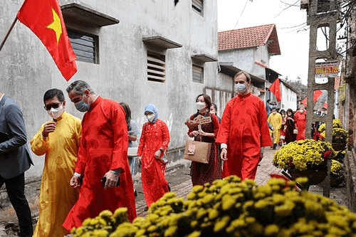 People in vibrant yellow and red robes stroll down a street, celebrating the Tet holiday with joy and tradition.